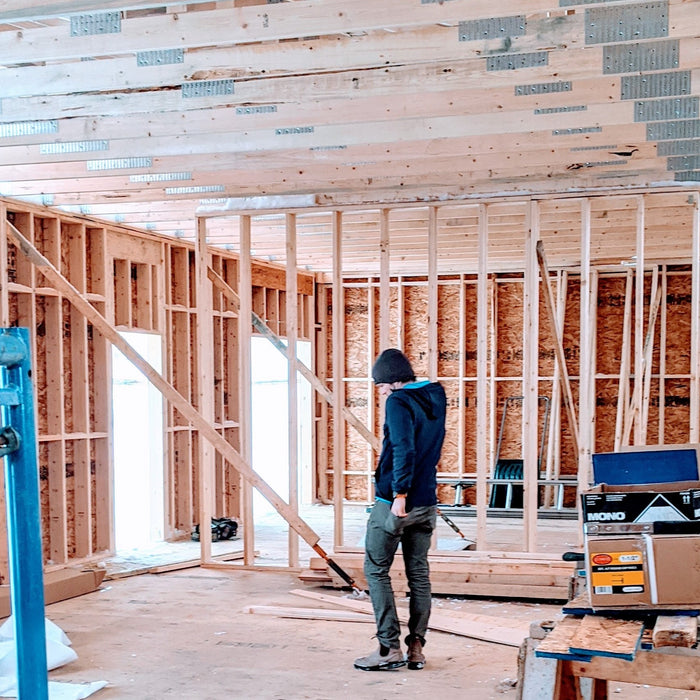 Image of Todd the co-founder of Alkeme standing in the production space as it's being built.  Walls are down to the studs as its being built.