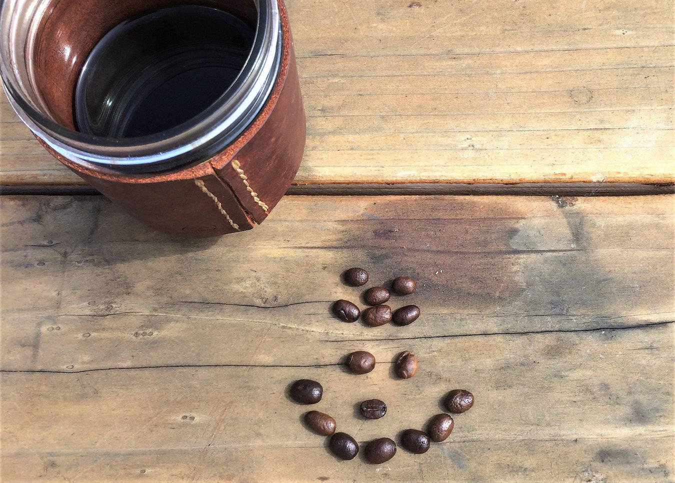 Mug of Adaptogenic Coffee on a plank backdrop with a smiley face of coffee beans